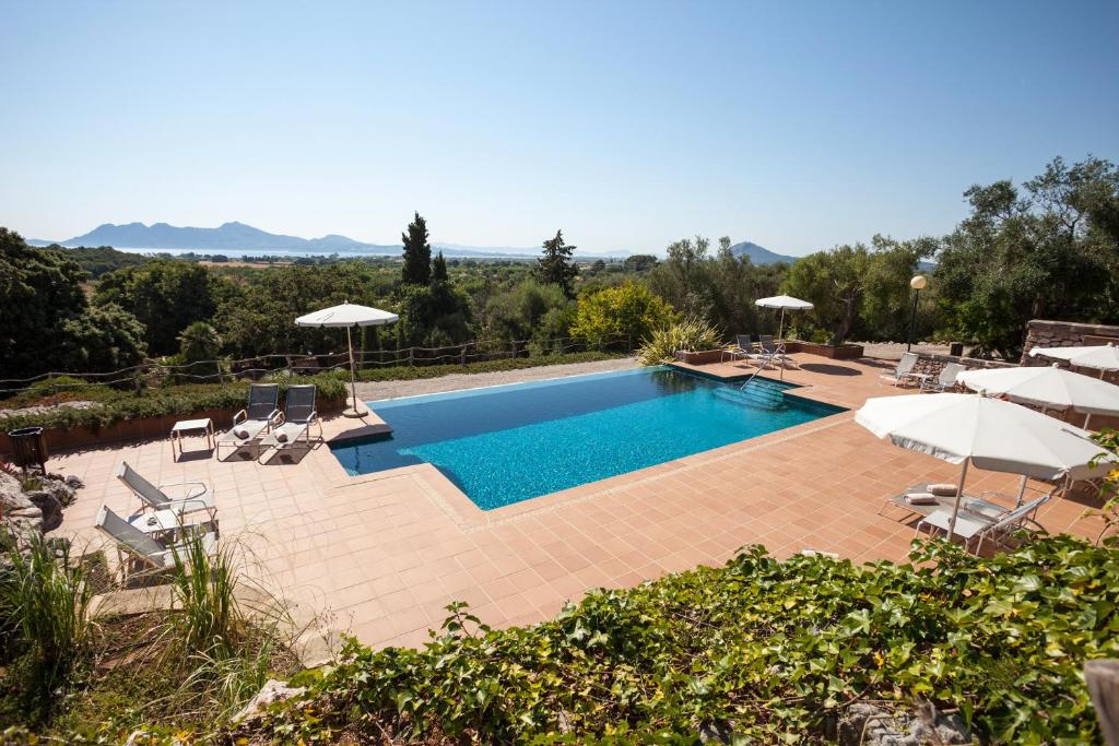 einen Pool mit Sonnenschirmen und Stühlen sowie einen Pool in der Unterkunft Hotel Llenaire in Port de Pollença