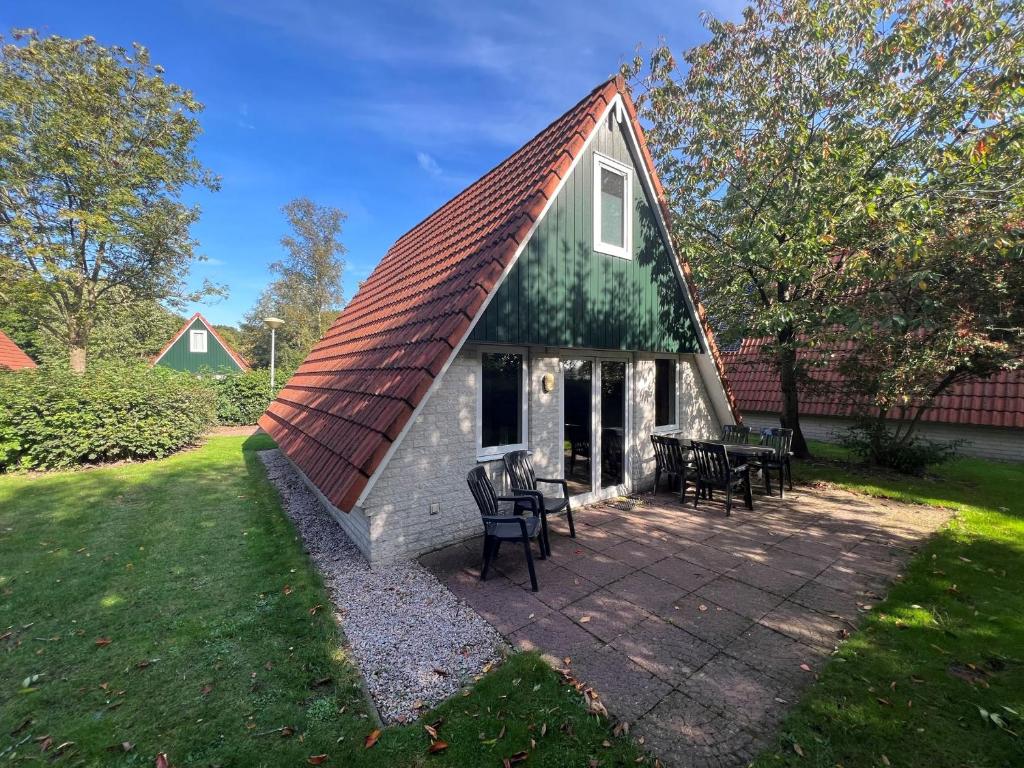 a house with a thatched roof on a patio at Het Familie Boshuisje - vakantiewoning op prachtig park met veel faciliteiten inc ligbad in Gramsbergen