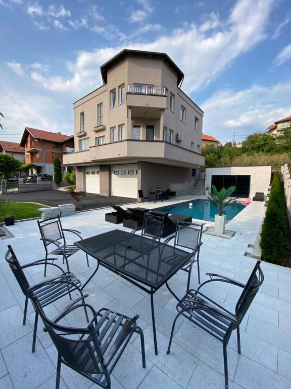 a patio with chairs and a table in front of a building at Villa Sunrise with swimming pool in Sarajevo