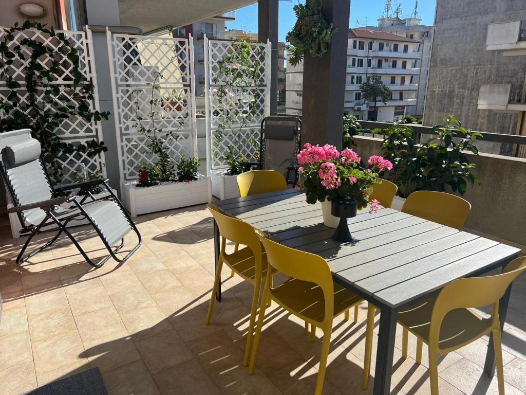 einen Tisch und Stühle auf einem Balkon mit rosa Blumen in der Unterkunft LA MALFA 48 in Ragusa