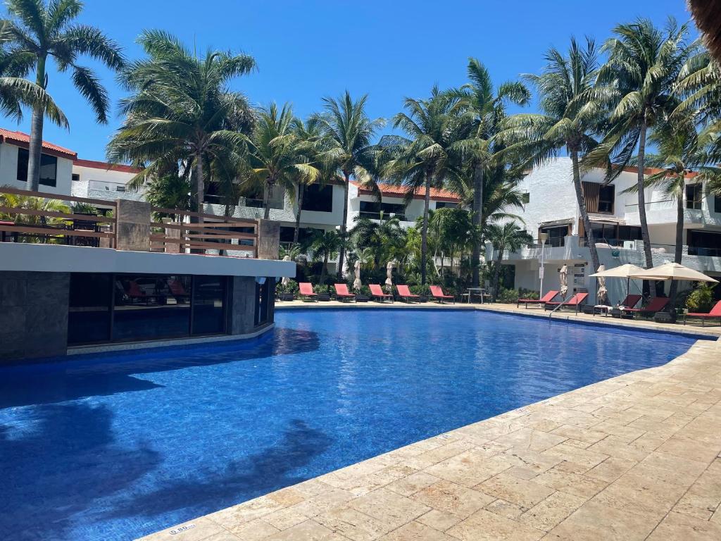 una gran piscina con palmeras y edificios en Sina Suites, en Cancún