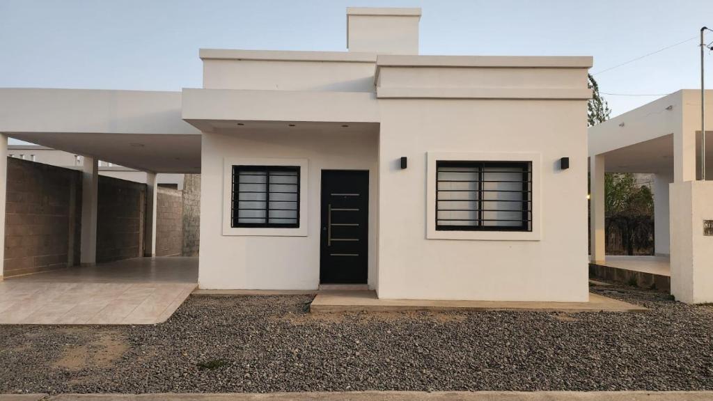 a white house with a black door and windows at DEPARTAMENTOS CIELO DE CAFAYATE in Cafayate