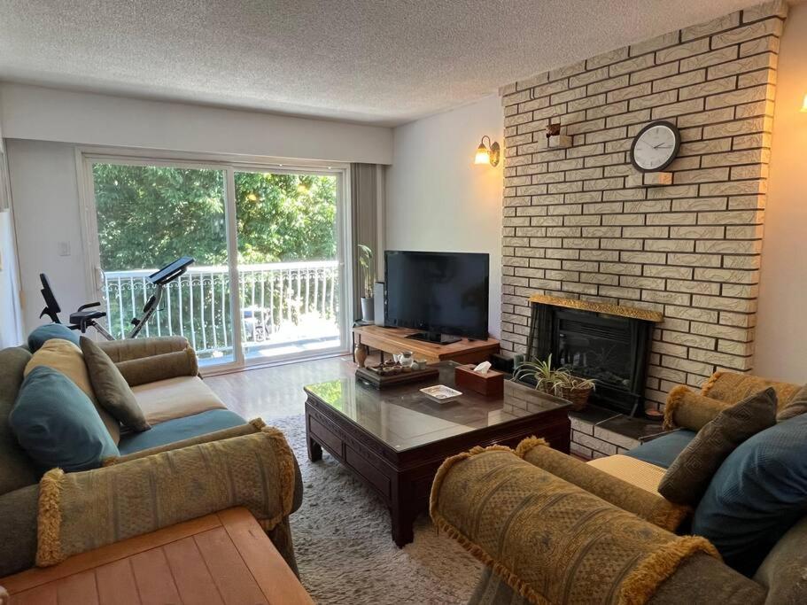 a living room with two couches and a fireplace at Two Bedrooms Marpole Vancouver in Vancouver
