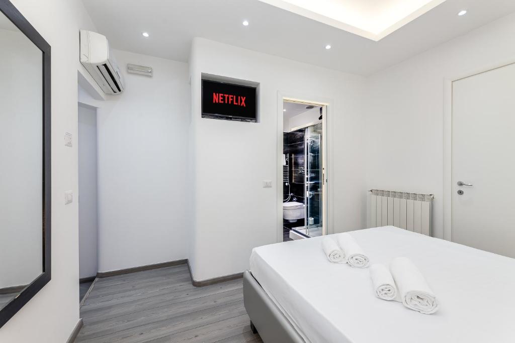 a white bed in a room with a sign on the wall at Spagna Boutique Suites in Rome