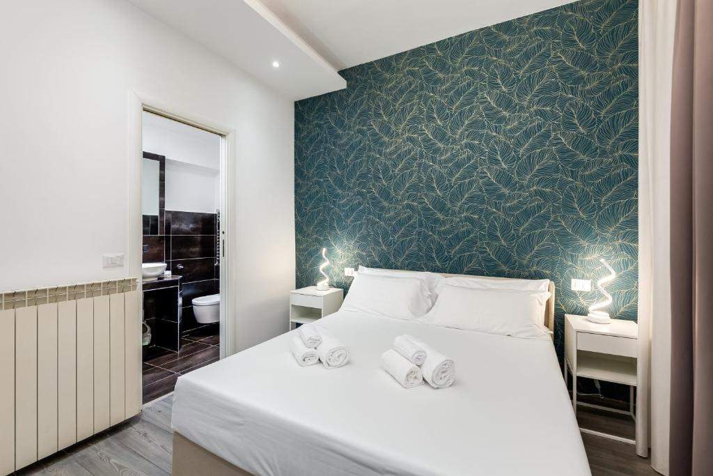 a bedroom with a white bed with a green wall at Spagna Boutique Suites in Rome