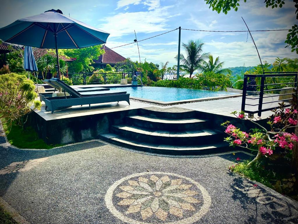 una piscina con panchina e ombrellone di Dmas Huts Lembongan a Nusa Lembongan