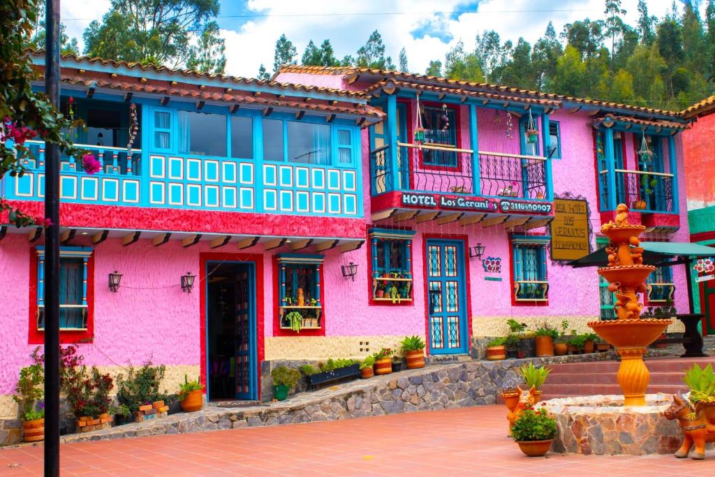 um edifício rosa e azul com uma fonte na frente em Hotel Los Geranios em Duitama