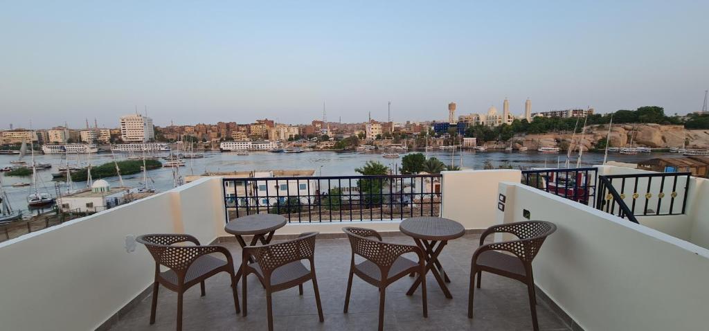 a balcony with four chairs and a table and a river at FADL Kato in Aswan
