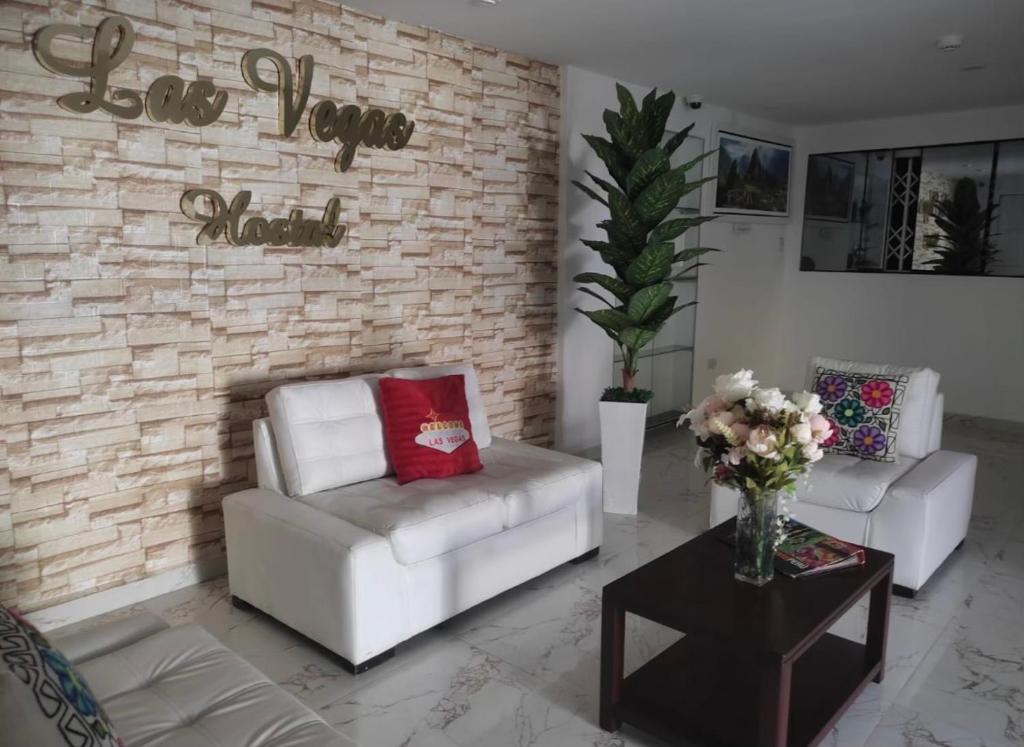 una sala de estar con 2 sofás blancos y una pared de ladrillo en Hostel Las Vegas en Lima