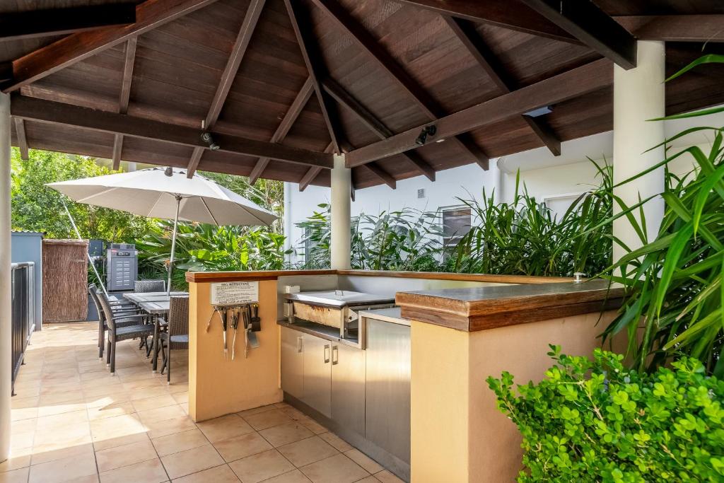 an outdoor kitchen with an umbrella on a patio at Byron Getaway @ Eco Beach in Byron Bay