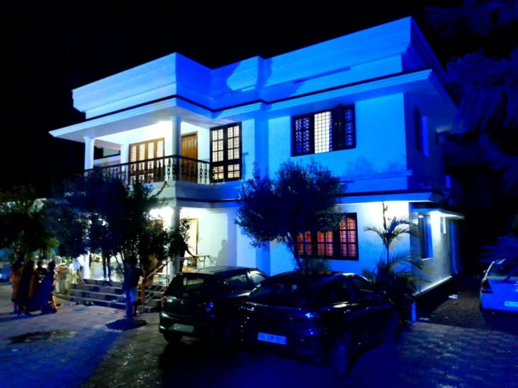 une maison éclairée en bleu avec une voiture garée devant dans l'établissement Maydale homes, à Kottayam