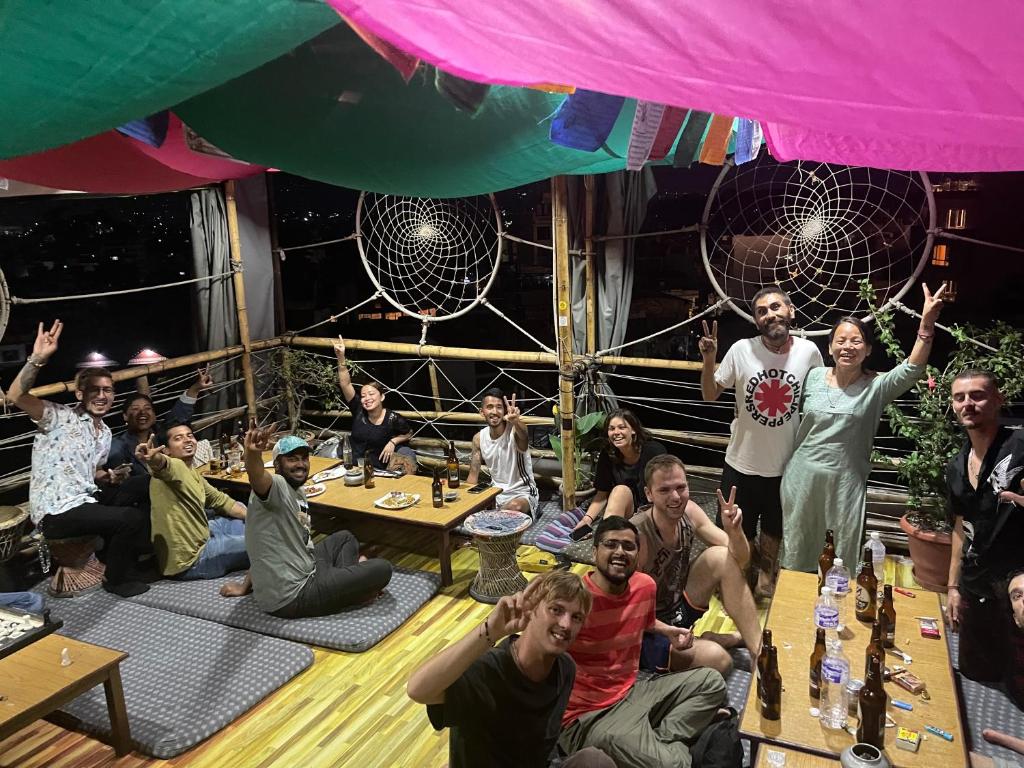 a group of people sitting around a table with their hands in the air at Planet Nomad Hostel in Kathmandu