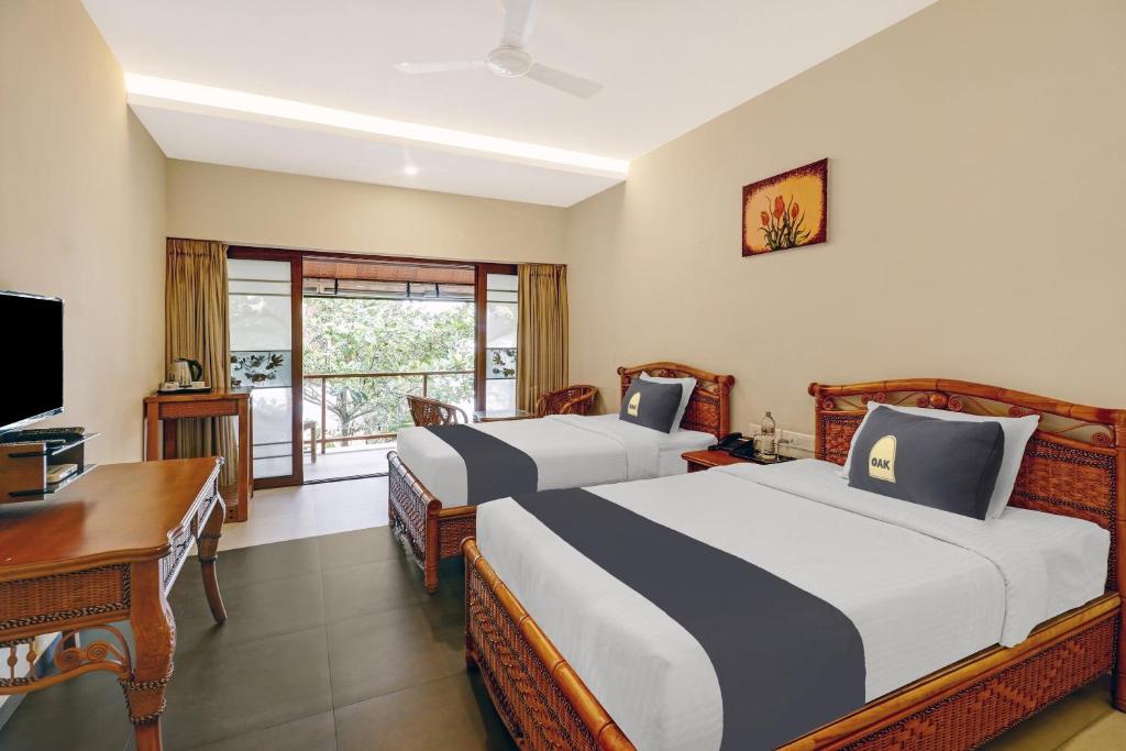 een hotelkamer met 2 bedden, een bureau en een televisie bij Townhouse OAK Edassery's Sealine Villa Stay in Cochin