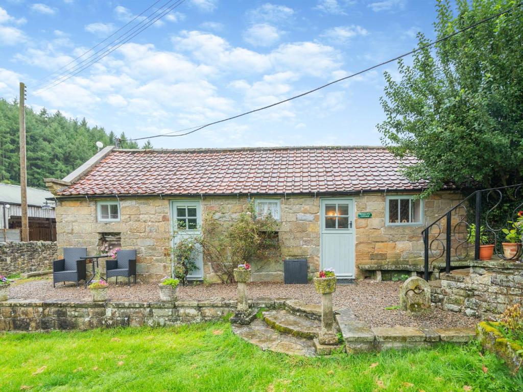 a stone cottage with a blue door in a yard at Foxglove - W43183 in Hawnby