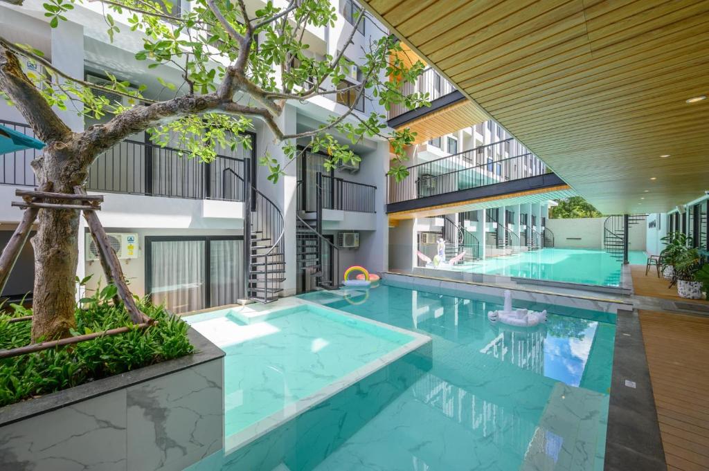 uma piscina interior com uma árvore num edifício em Tour De Phuket Hotel - SHA Plus em Thalang