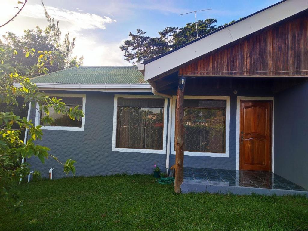 a blue house with a wooden door and a yard at HeCo House in Monteverde Costa Rica