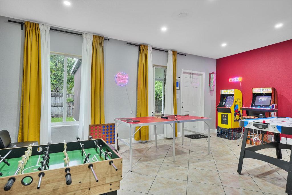 a room with two ping pong tables and a video game at Vacay Spot Gables 4 to 23 Guest GameRoom 2 Kitchens 2 BBQ, 2 BAR, Backyard, Patio, Prime LOC! 6 blocks away from Bars, Nite Clubs, Res, Shops in Miami