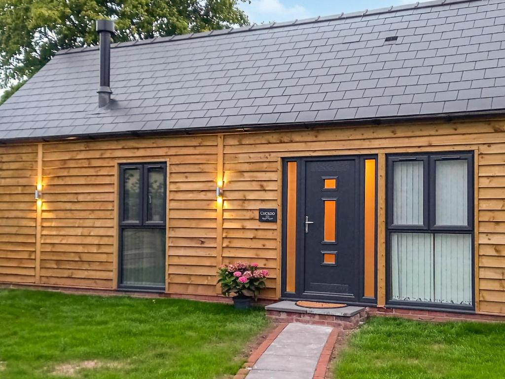 Casa de madera con puerta y ventanas negras en Cuckoo Lodge - Uk42541 en Winforton