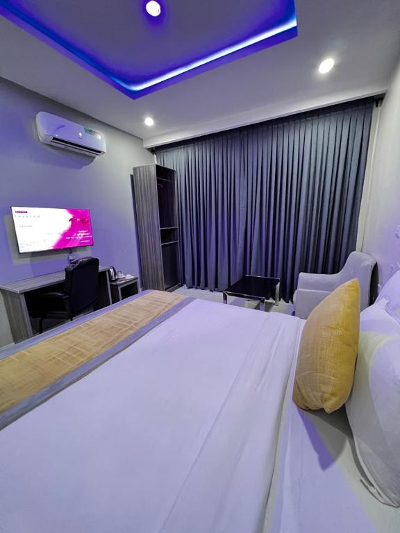 a bedroom with a large bed and a flat screen tv at Rigg Hotel in Apapa Eleko