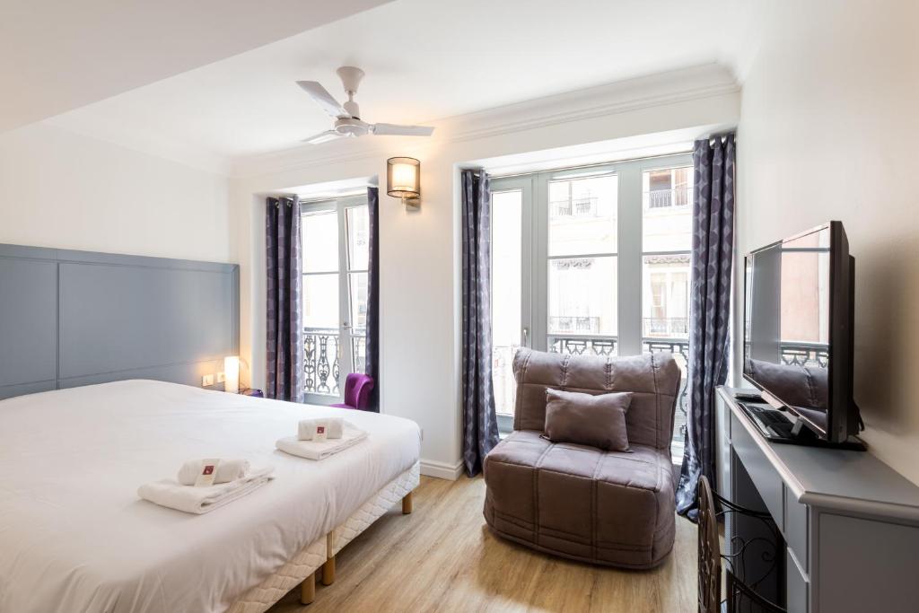 une chambre avec un lit, une chaise et une télévision dans l'établissement Les Capucins - Lyon 1er, à Lyon