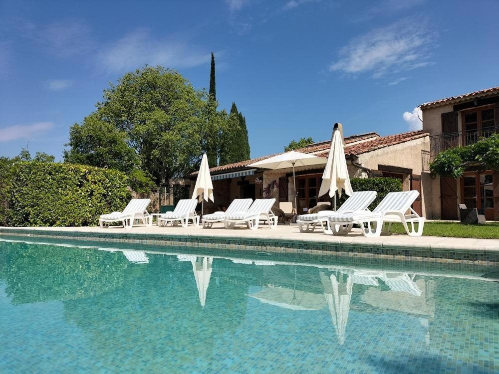 un groupe de chaises et de parasols à côté d'une piscine dans l'établissement Le pre des huppes, à Salernes