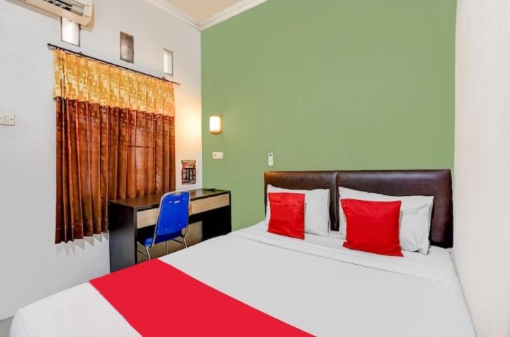 a bedroom with two beds with red pillows and a desk at Pondok Inap Shofwa in Sedati