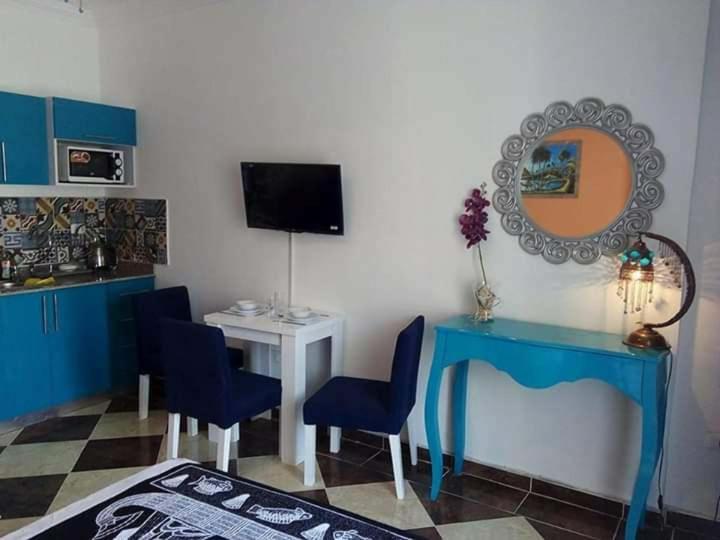 Habitación con mesa azul, sillas y TV. en Exoticky apartman en Hurghada