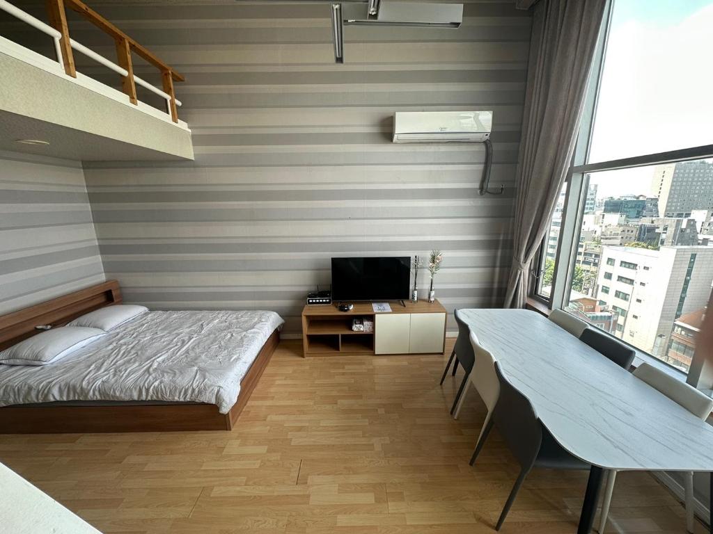 um quarto com uma cama, uma secretária e uma televisão em Hongdae Guesthouse2 1min from Hongik Uni station Exit #1 em Seul