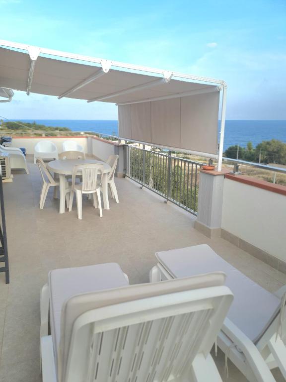 a balcony with white chairs and tables and the ocean at Appartamento - Plemmirio - Villa Maria Serena in Syracuse
