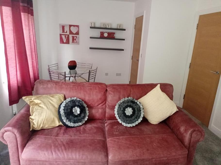 a living room with a red couch with pillows on it at Stansted Airport Serviced Accommodation x DM for Weekly x Monthly Deals by D6ten Homes Ltd in Takeley