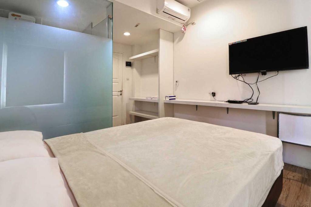 a bedroom with a bed and a flat screen tv at Rumah Kayu Manis Bintaro in Jakarta