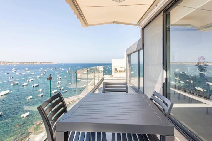 - une table avec des chaises et une vue sur l'eau dans l'établissement SkyView Penthouse, Mell_4, à Mellieħa