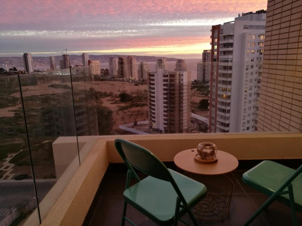 een tafel en stoelen op een balkon met uitzicht op de stad bij Exquisito y amplio departamento en el mejor sector de Reñaca in Concón