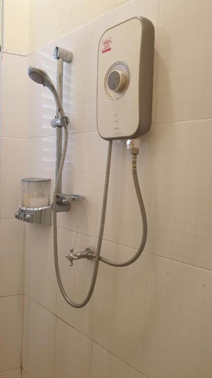 a shower in a bathroom with a hose on a wall at Thunyaporn Hostel in Trang