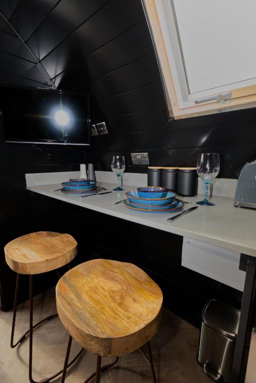 a counter with two stools and plates and wine glasses at North Coast 500 Pods in Achmelvich