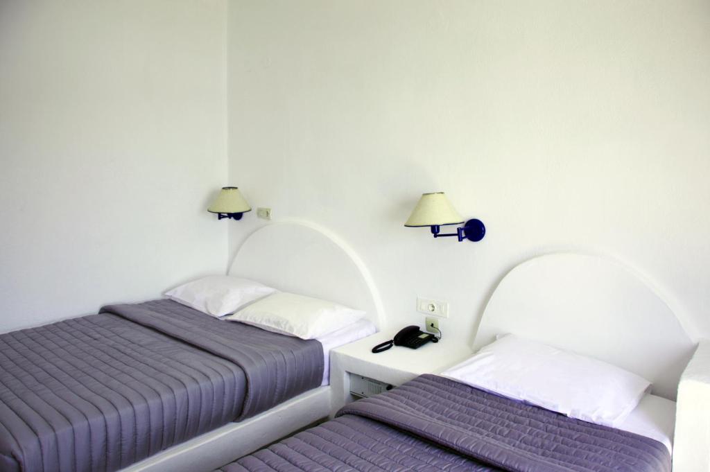 two beds in a room with purple sheets and lamps at Patmos Paradise Hotel in Kámbos