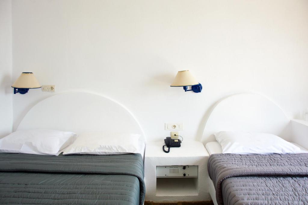 a bedroom with two beds and two lamps on the wall at Patmos Paradise Hotel in Kámbos