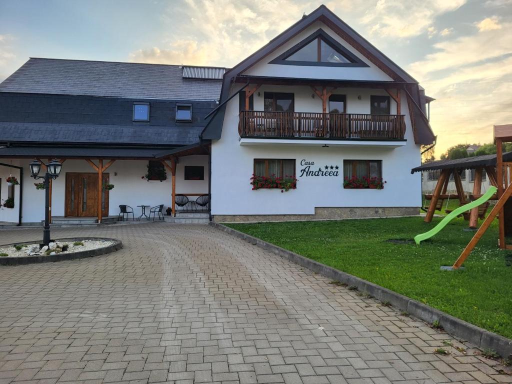 un edificio blanco con un parque infantil delante de él en Casa Andreea en Vatra Dornei