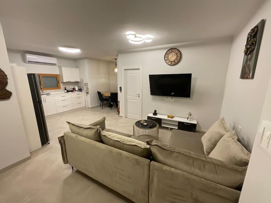 a living room with a couch and a clock on the wall at דירת ים in Kinneret