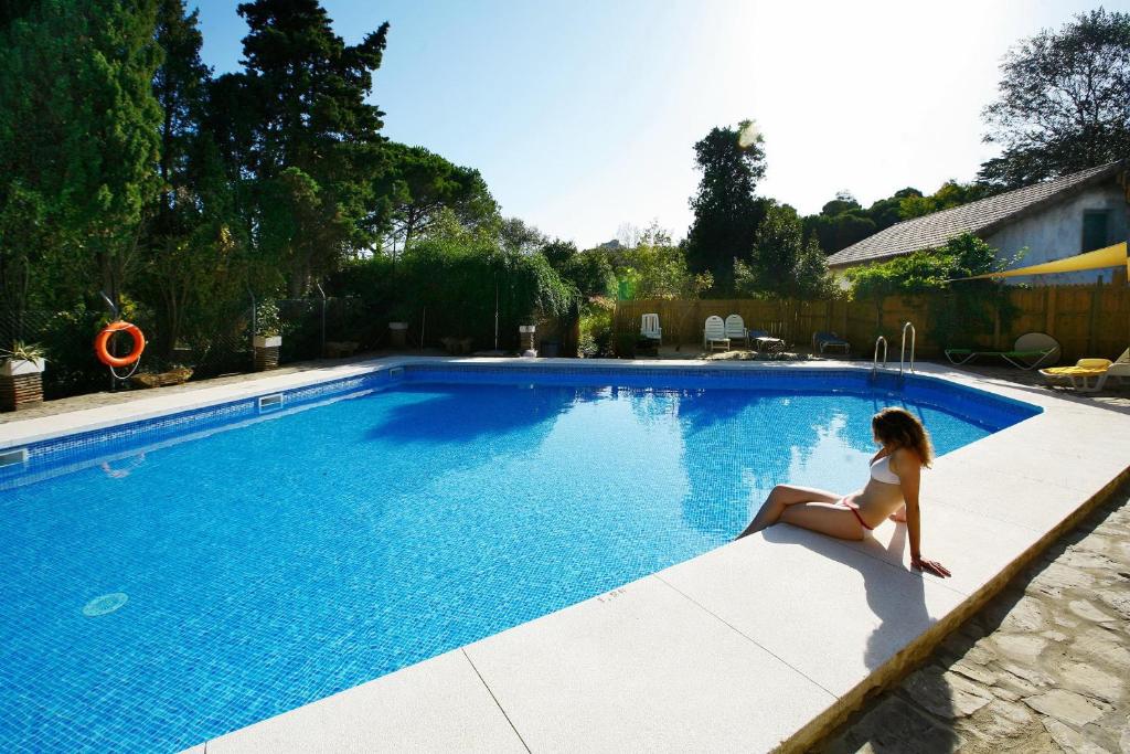 una mujer sentada en el borde de una piscina en Complejo Rural Huerta Grande, en Algeciras