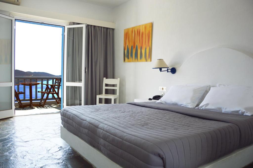 a bedroom with a large bed and a balcony at Patmos Paradise Hotel in Kámbos