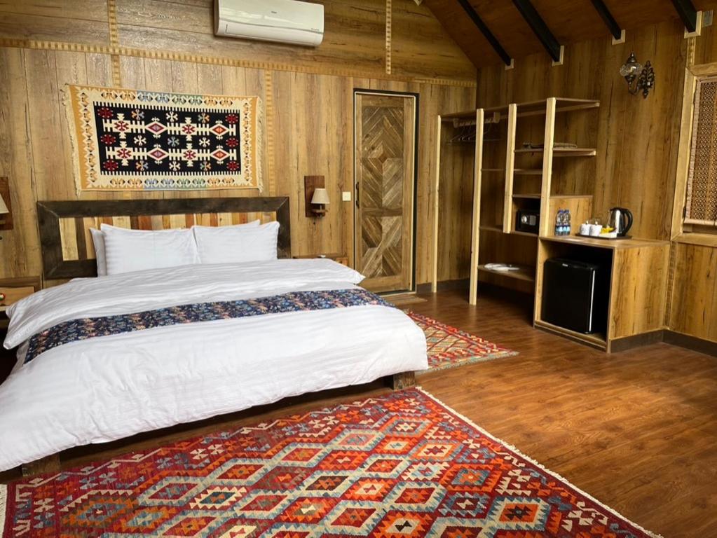een slaapkamer met een groot bed en een tapijt bij The 2 Magpies in Alīābād