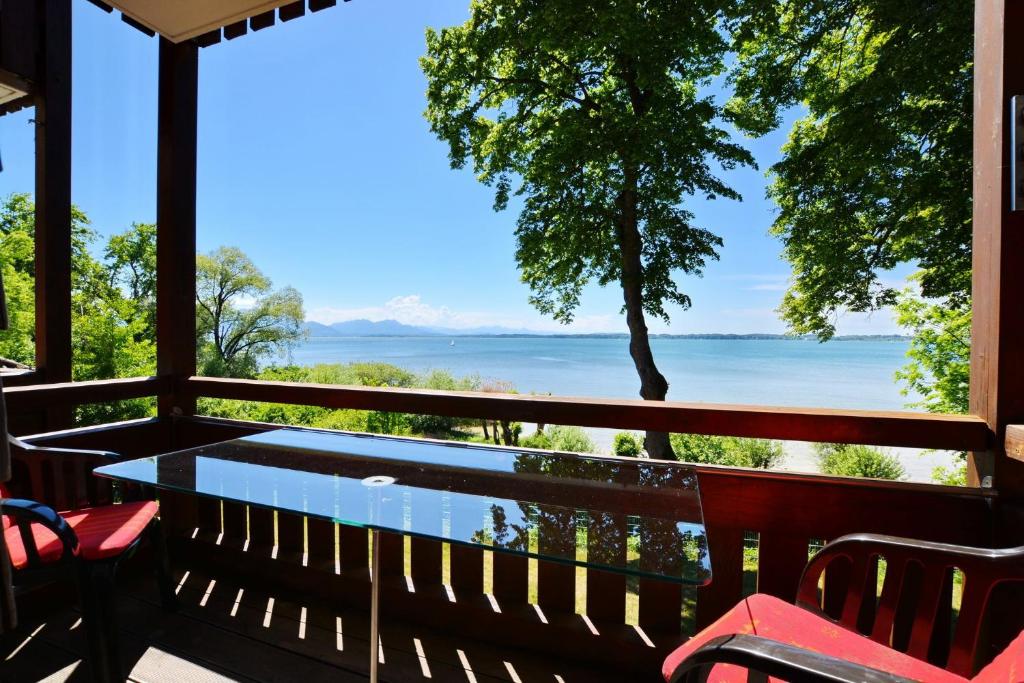 eine Veranda mit einem Tisch und Stühlen sowie Blick auf das Wasser in der Unterkunft Ferienresidenz Chiemseestrand - Apartment 14 in Chieming