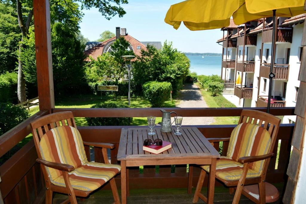 een tafel en stoelen op een balkon met uitzicht op het water bij Ferienresidenz Chiemseestrand - Apartment 28 in Chieming