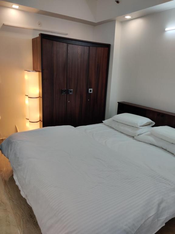 a bedroom with a large white bed with a wooden cabinet at Vista Vibes in Chennai