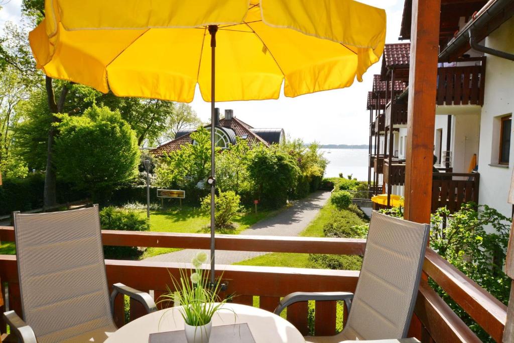 een tafel met een gele parasol op een balkon bij Ferienresidenz Chiemseestrand - Chiemseesonne in Chieming
