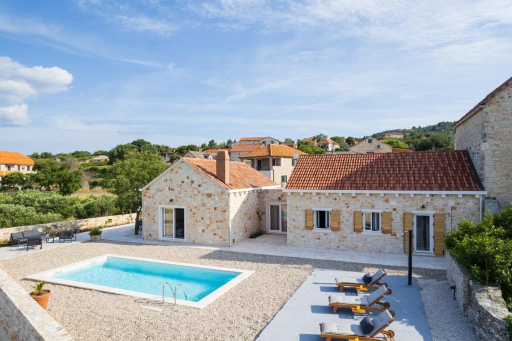einen Blick auf eine Villa mit einem Pool in der Unterkunft NEW! Stone Villa Olim Civitas with 3 bedrooms, private pool, and sea views in Škrip