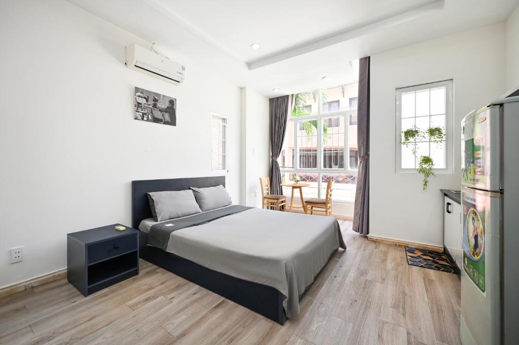 a bedroom with a bed and a table and a refrigerator at Cali Homestay in Ho Chi Minh City