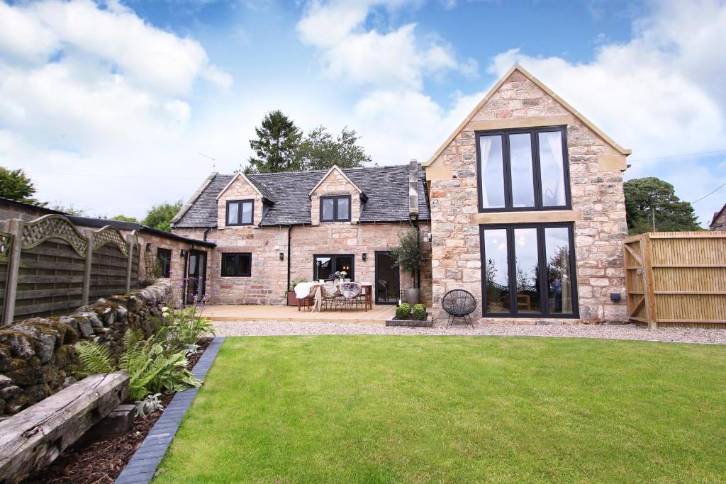 an exterior view of a stone house with a yard at Green Cottage Luxury Stay Peak District near Alton Towers in Stanton