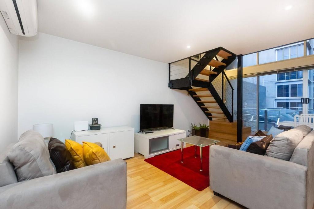 uma sala de estar com dois sofás e uma televisão em New York Lofted CBD Retreat with Pool and Parking em Melbourne